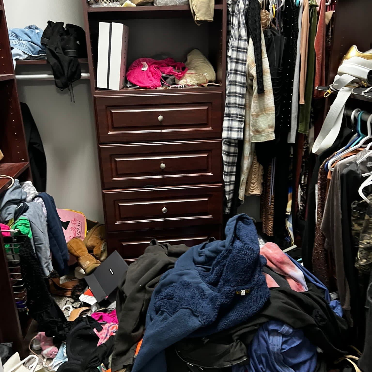 A closet with a lot of clothes and a dresser