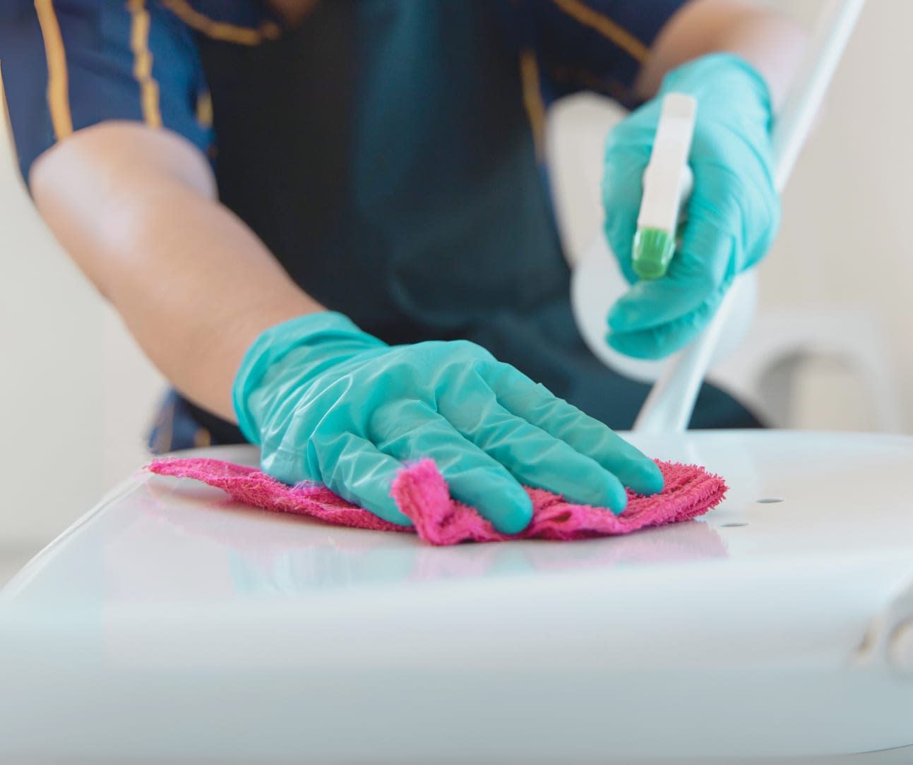 A person wearing gloves is cleaning a toilet with a cloth and a marker.