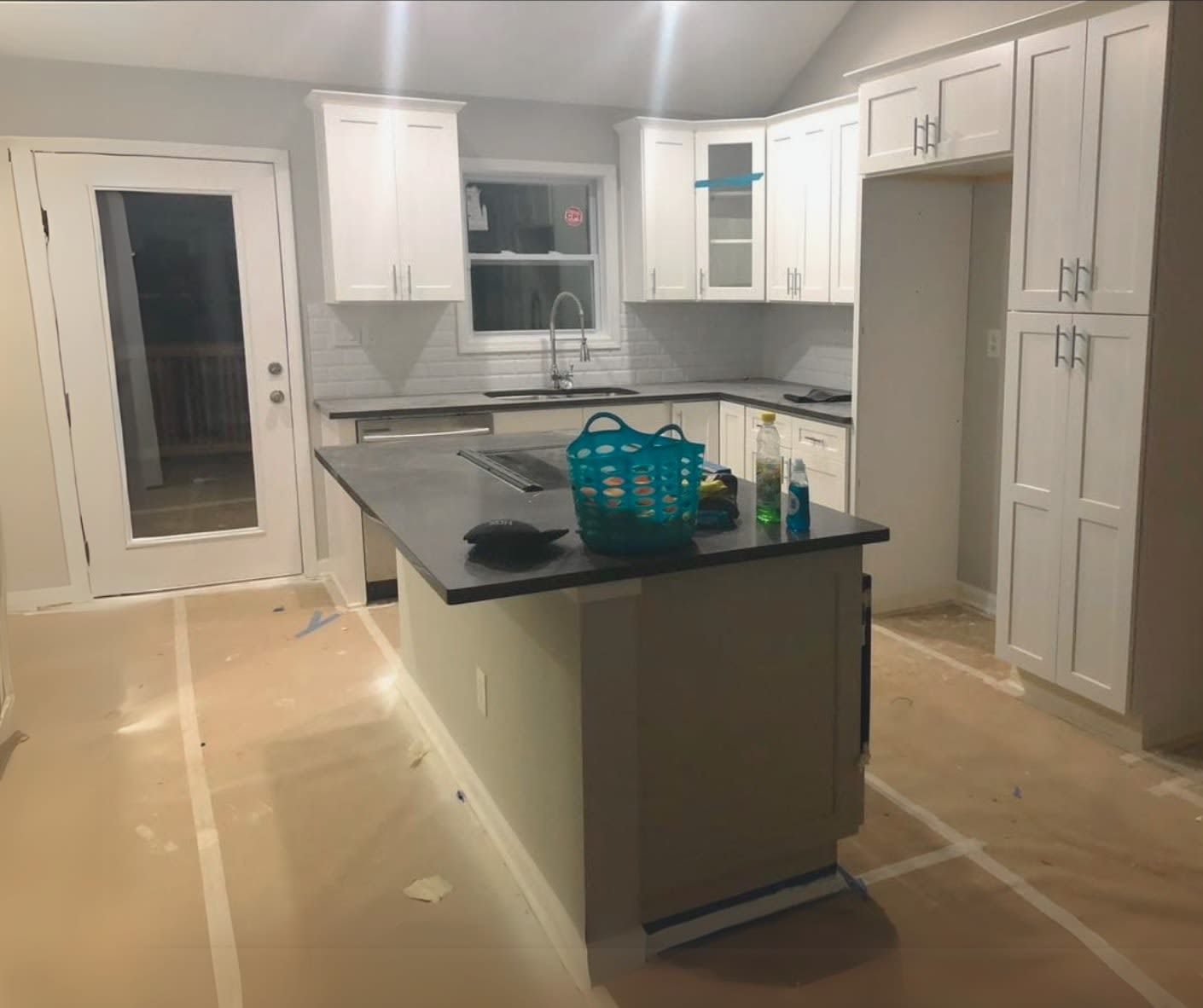 A kitchen with white cabinets and a large island in the middle.