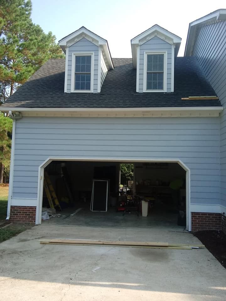 A blue house with a garage and a black roof