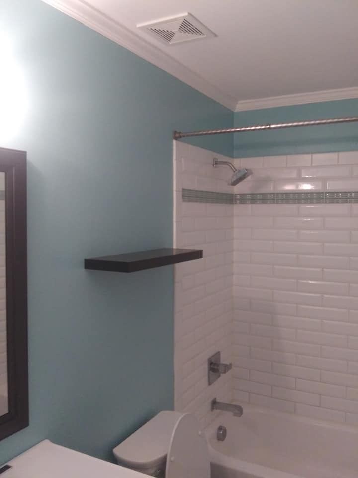 A bathroom with a toilet , tub , shower and mirror