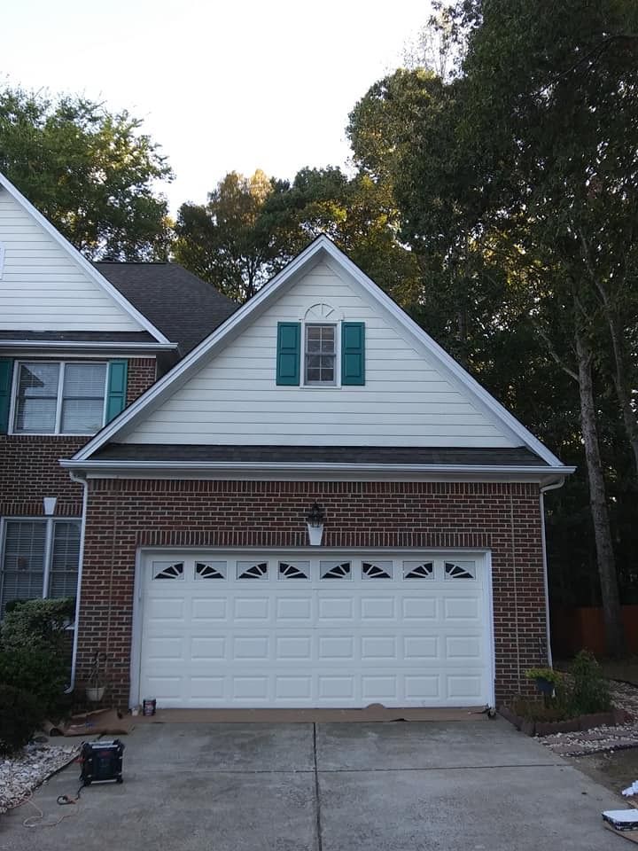 A brick house with a white garage door and green shutters