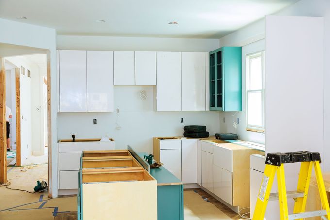 A kitchen under construction with a yellow ladder in the foreground.