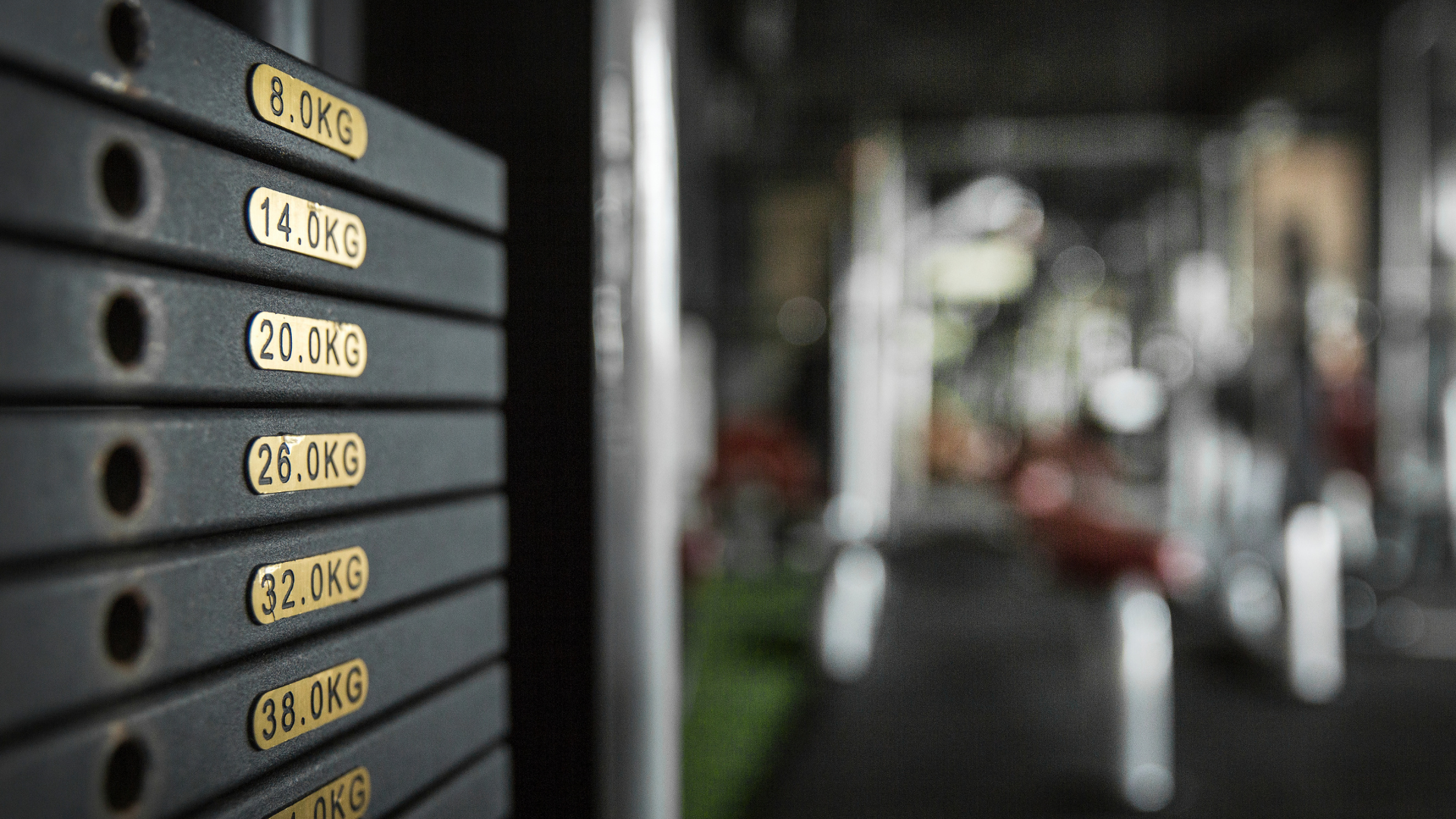 Weight stack in a gym, with labels showing weights in kilograms.