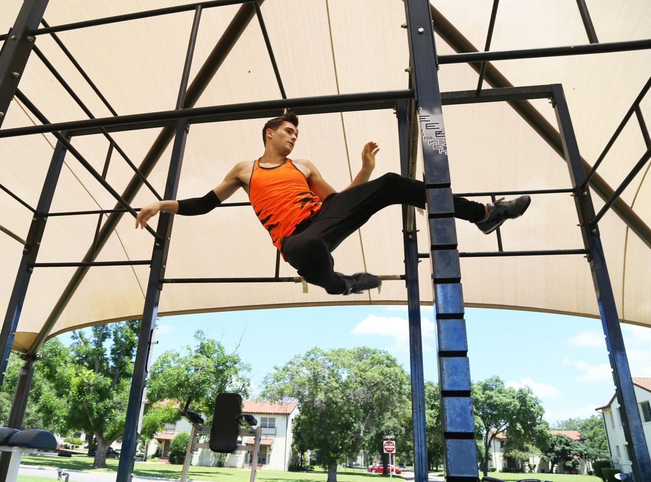 A person in a boxing stance inside a cage, lit by rays of light. Black and white photo.