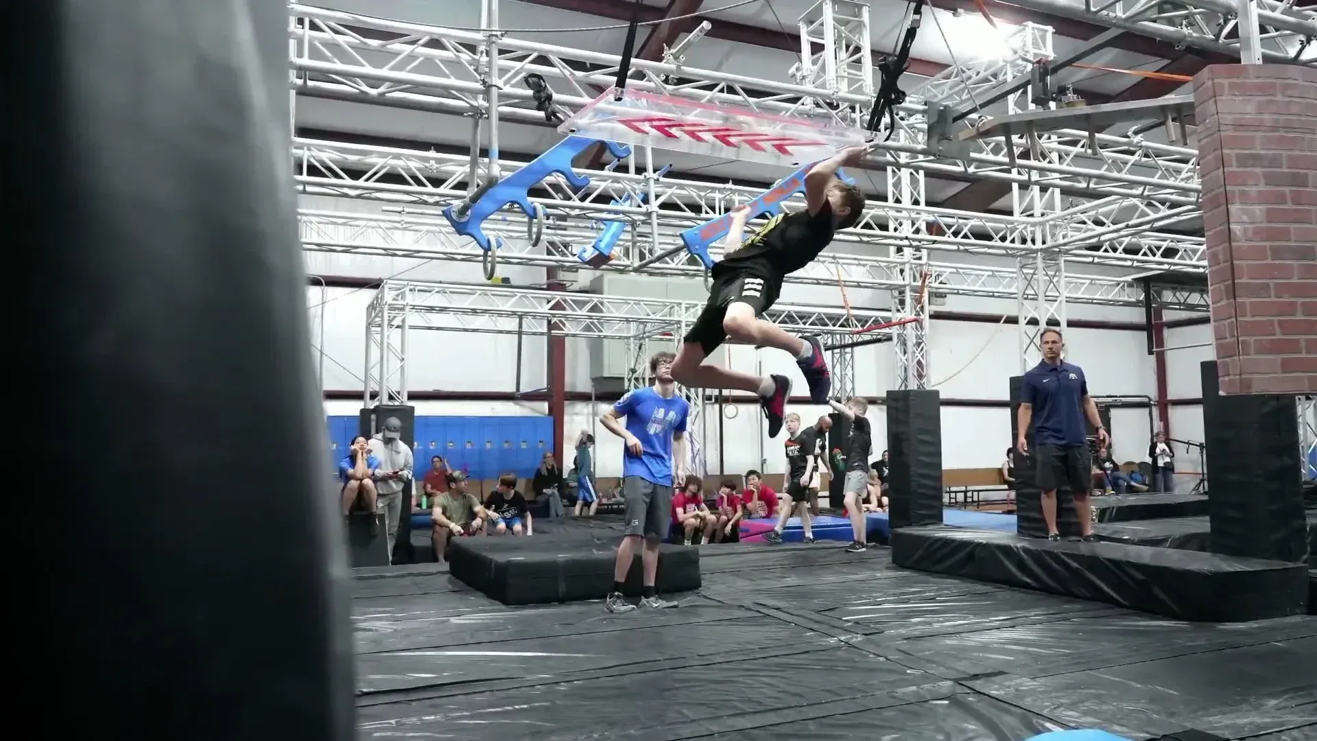 Black sneakers, ab roller, and dumbbells on a red exercise mat.