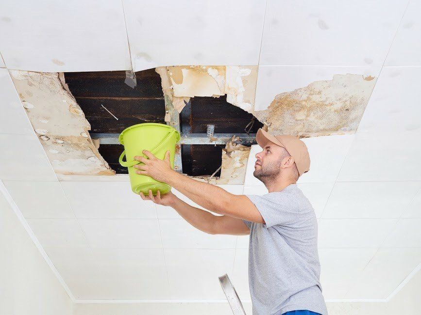 Man Holding a Bucket on a Broken Ceiling — Santa Barbara, CA — All American Roofing