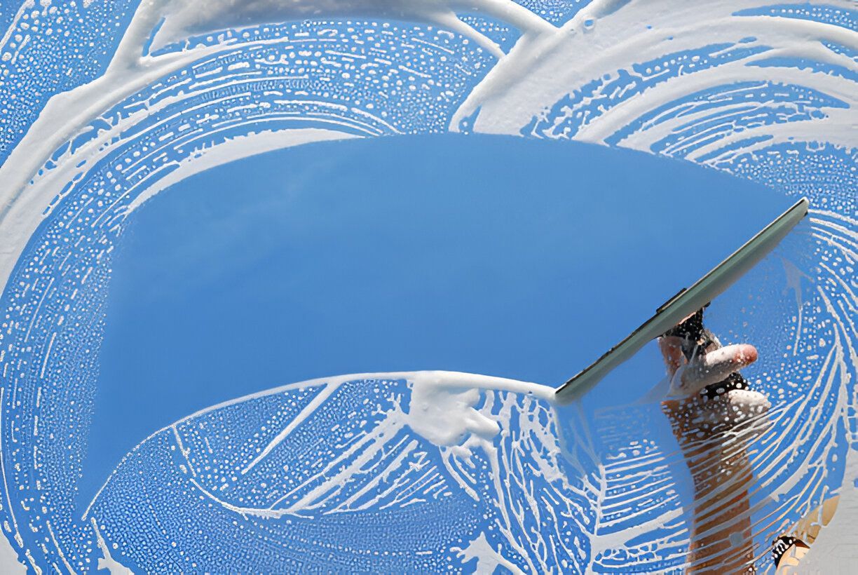 A person is cleaning a window with a squeegee.