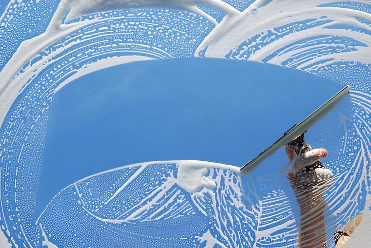 A person is cleaning a window with a squeegee.