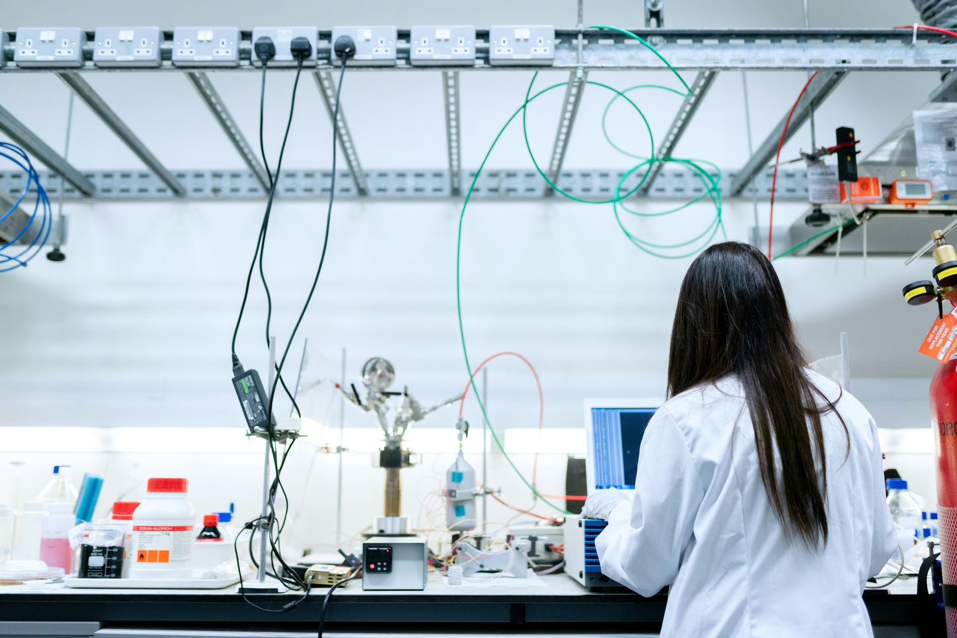Uma mulher de jaleco está trabalhando em um computador em um laboratório.