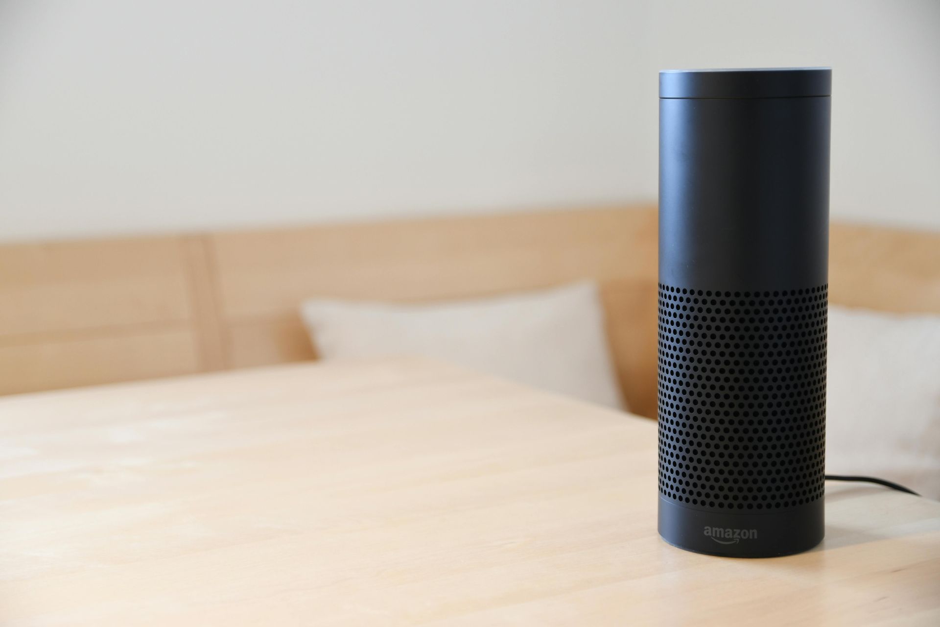 Um alto-falante Amazon Echo está sobre uma mesa de madeira.