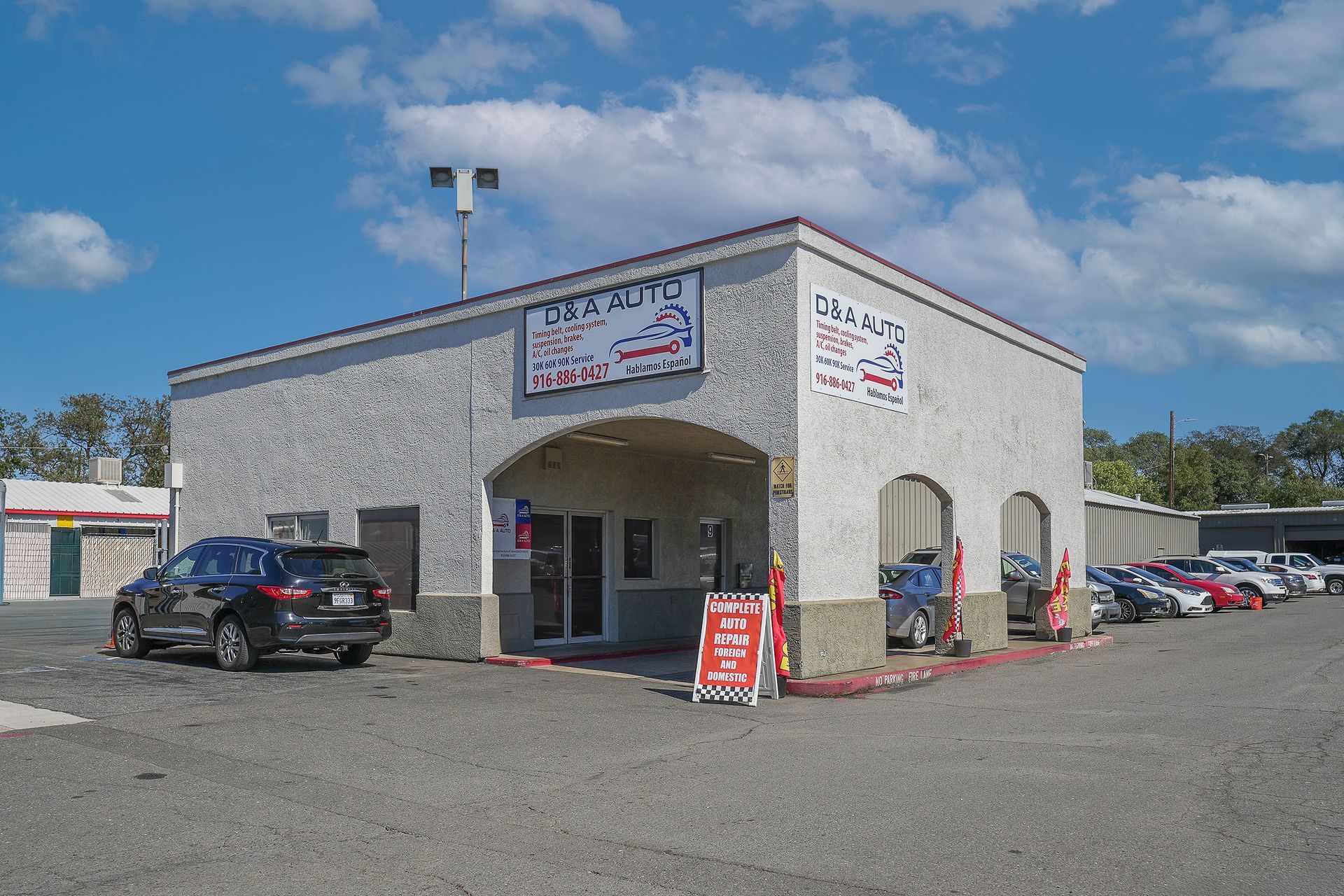 Auto repair shop exterior with parked cars under a blue sky. "O's Auto" sign is visible above the entrance.