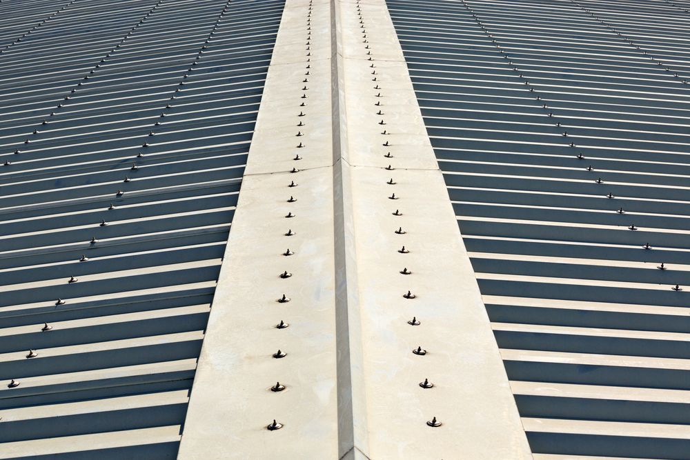 Shadows Cast Across a Concrete Surface With a Central Seam Dotted With Rivets — Darren Smith Roofing In Glendale, NSW
