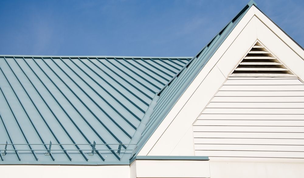 Blue Metal Roof With White Gable and Vent Against Blue Sky — Darren Smith Roofing In Kotara, NSW