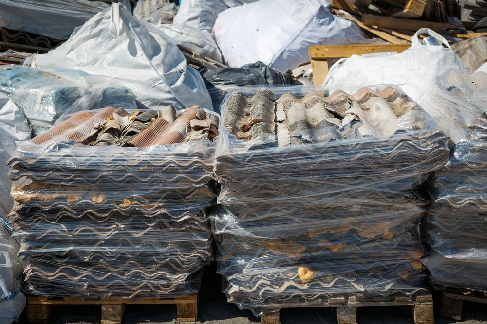 Stacked bundles of corrugated roofing tiles wrapped in plastic on pallets — Darren Smith Roofing In Glendale, NSW