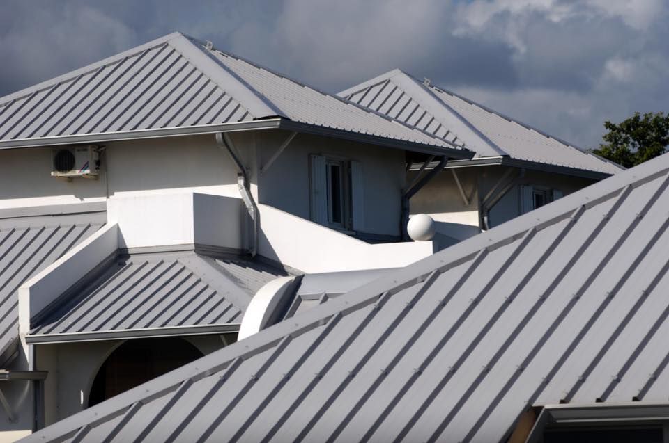 Gray Metal Roofs on a White Building Under a Cloudy Sky — Darren Smith Roofing In Kotara, NSW
