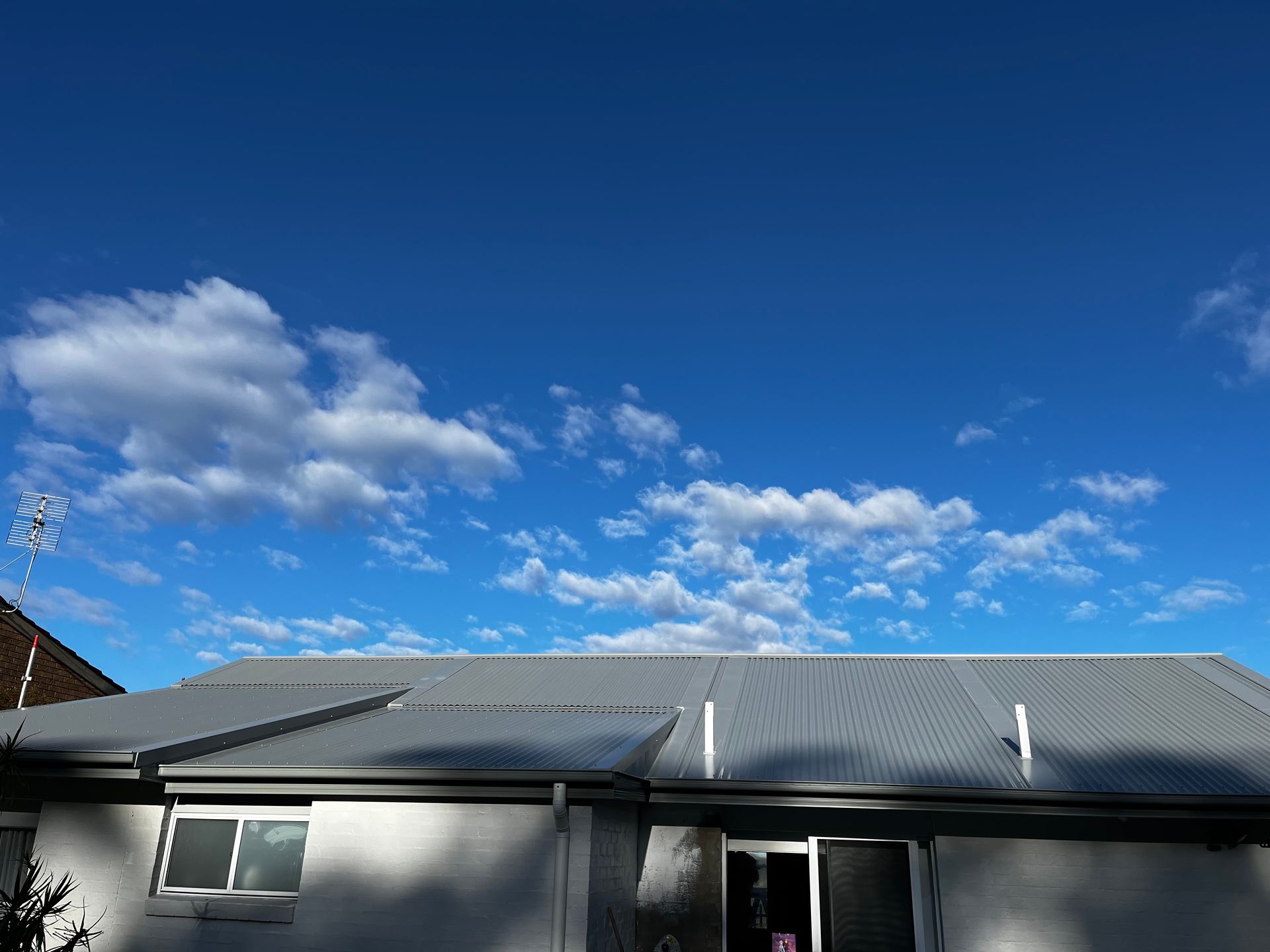 Metal Roof with Plastic Siding Drainage System, Soffits, and Eaves against a Clear Blue Sky — Guttering in Gosford, NSW