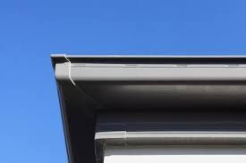 A close up of a gutter on a house against a blue sky.