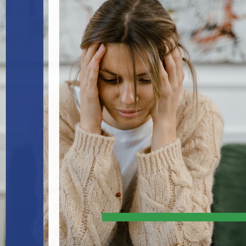 Woman with hands on head, looking down, possibly stressed or in pain, indoors.