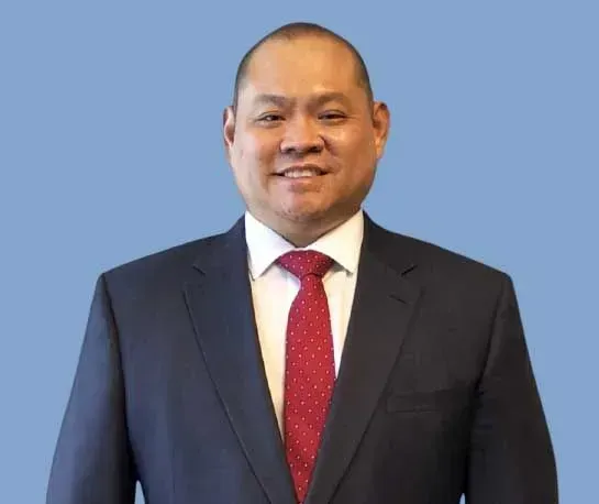 A man wearing a hard hat and goggles is standing in a room.