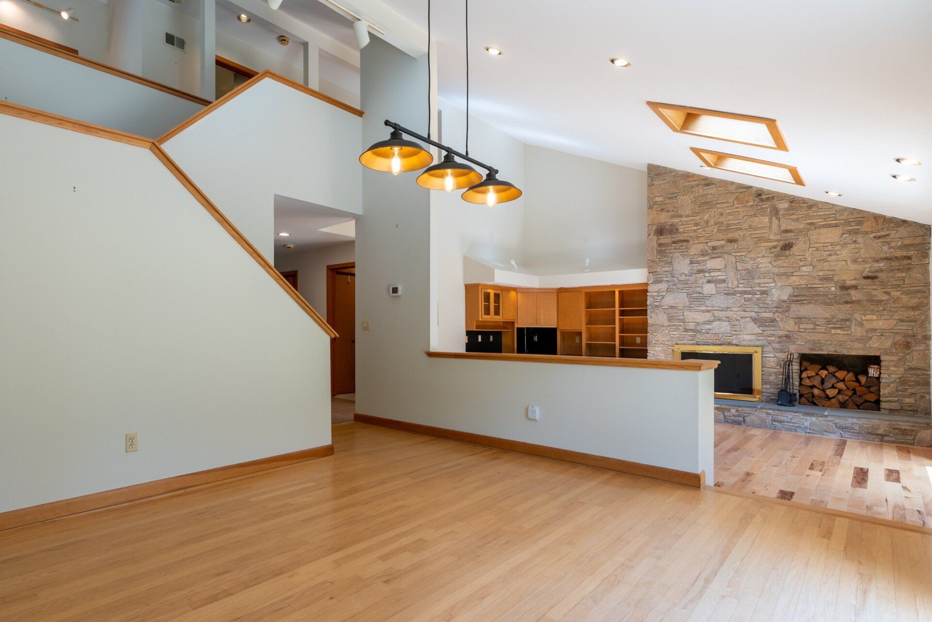 An empty living room with hardwood floors and a fireplace