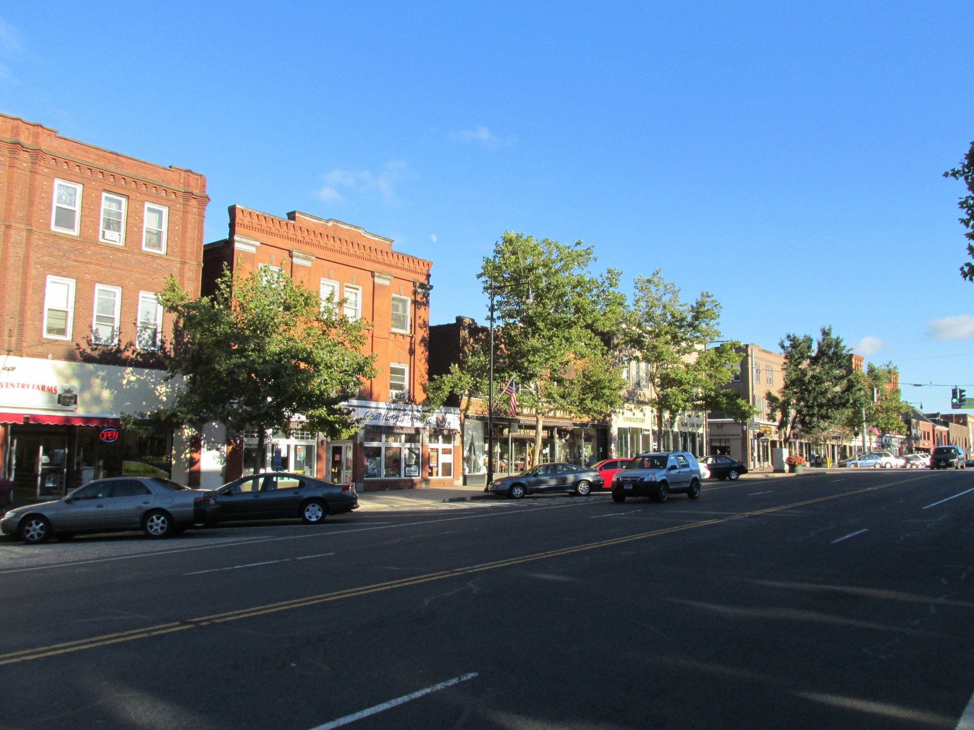 A row of cars are parked on the side of a city street