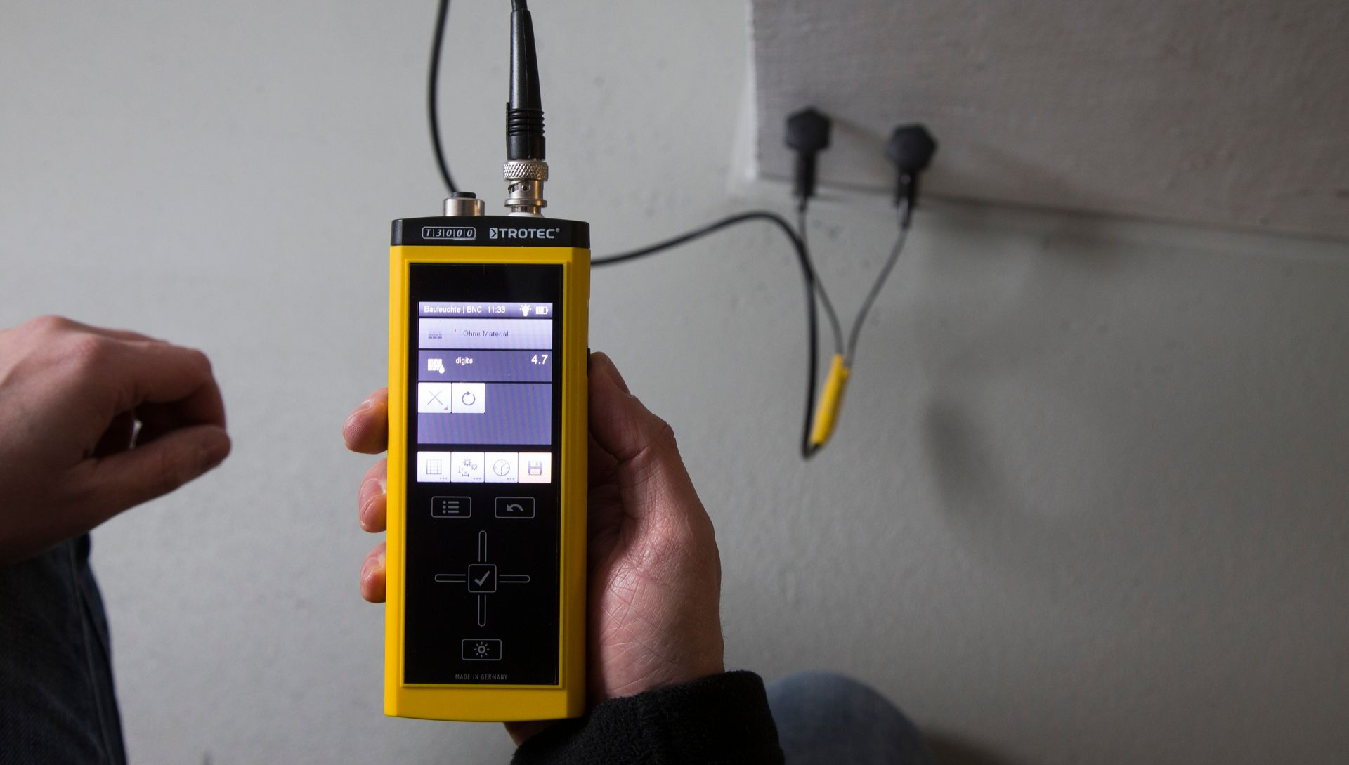 Ein Mann hält ein gelbes Messgerät in der Hand