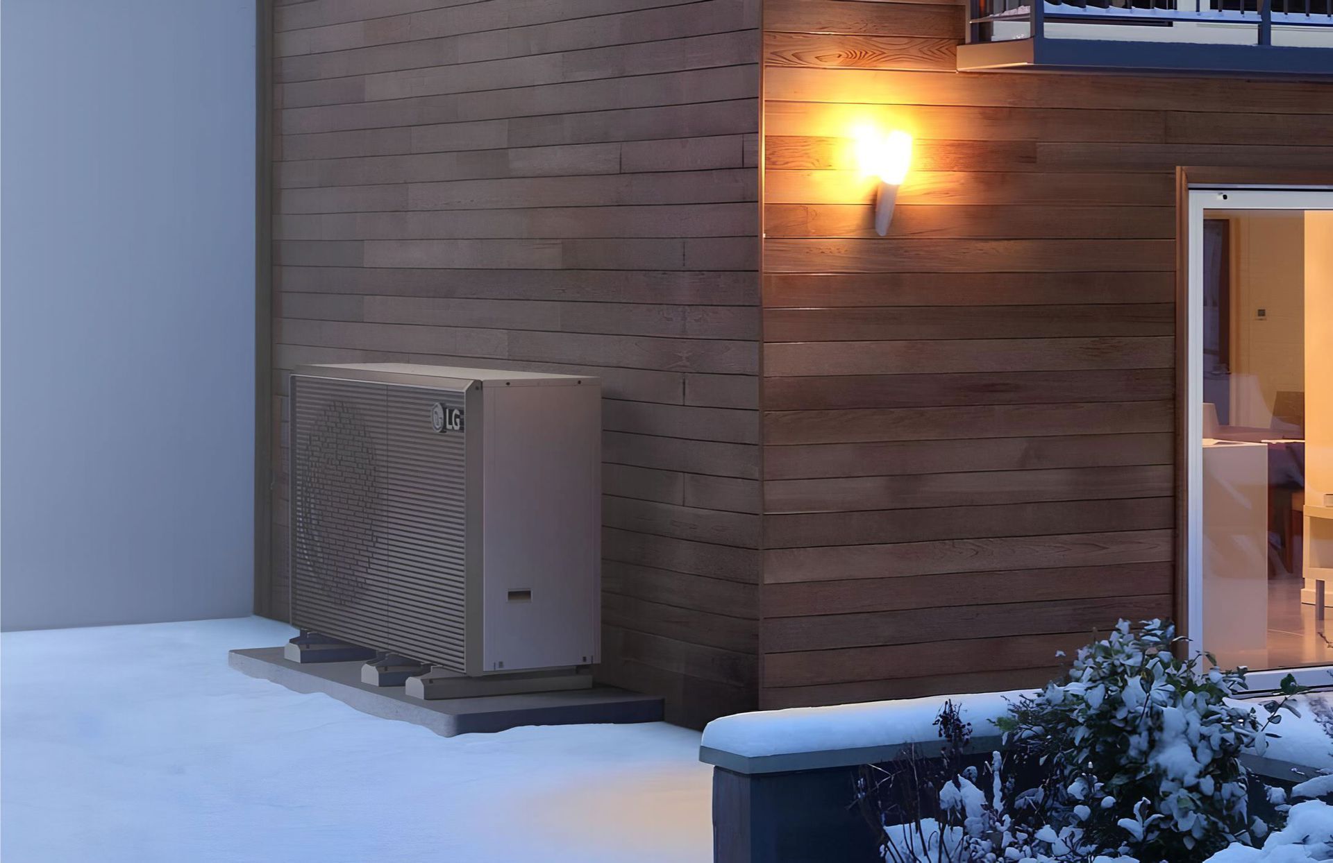Wärmepumpe steht im Aussenbereich eines Hauses im Winter. 