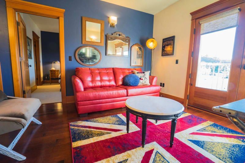 A living room with a red couch , a coffee table , and a rug.