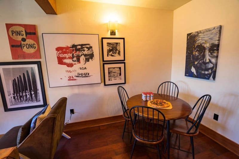 A dining room with a table and chairs and paintings on the wall