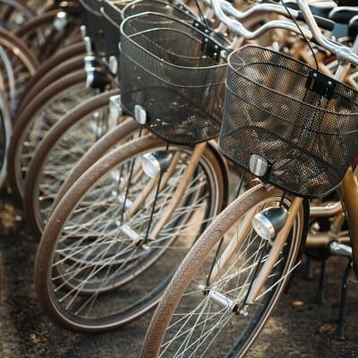 A row of bicycles with baskets are parked next to each other.