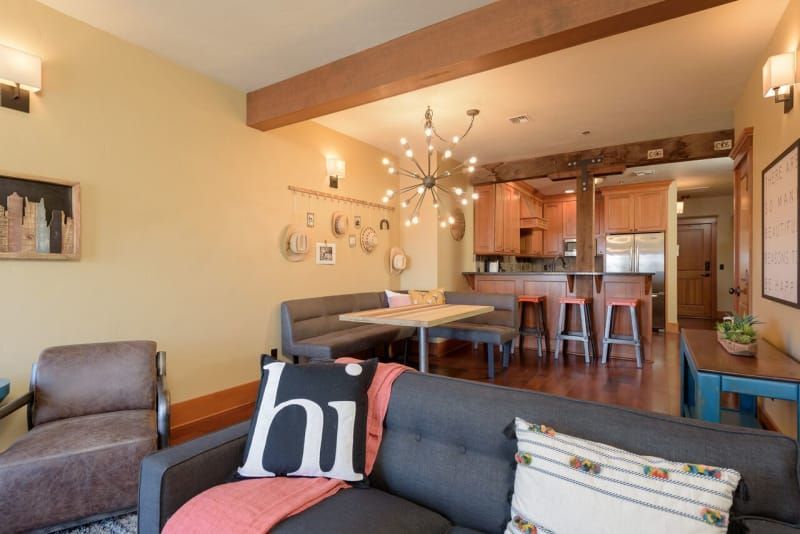 A living room with a couch , chair , table and a pillow that says hi.