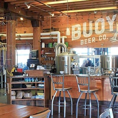 A restaurant with tables and chairs and a sign that says buoy beer co.