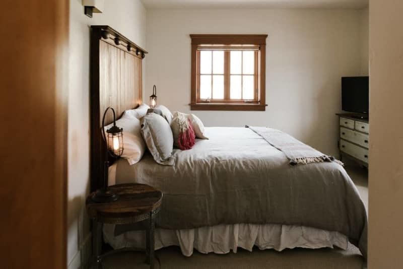 A bedroom with a bed , dresser , television and window.