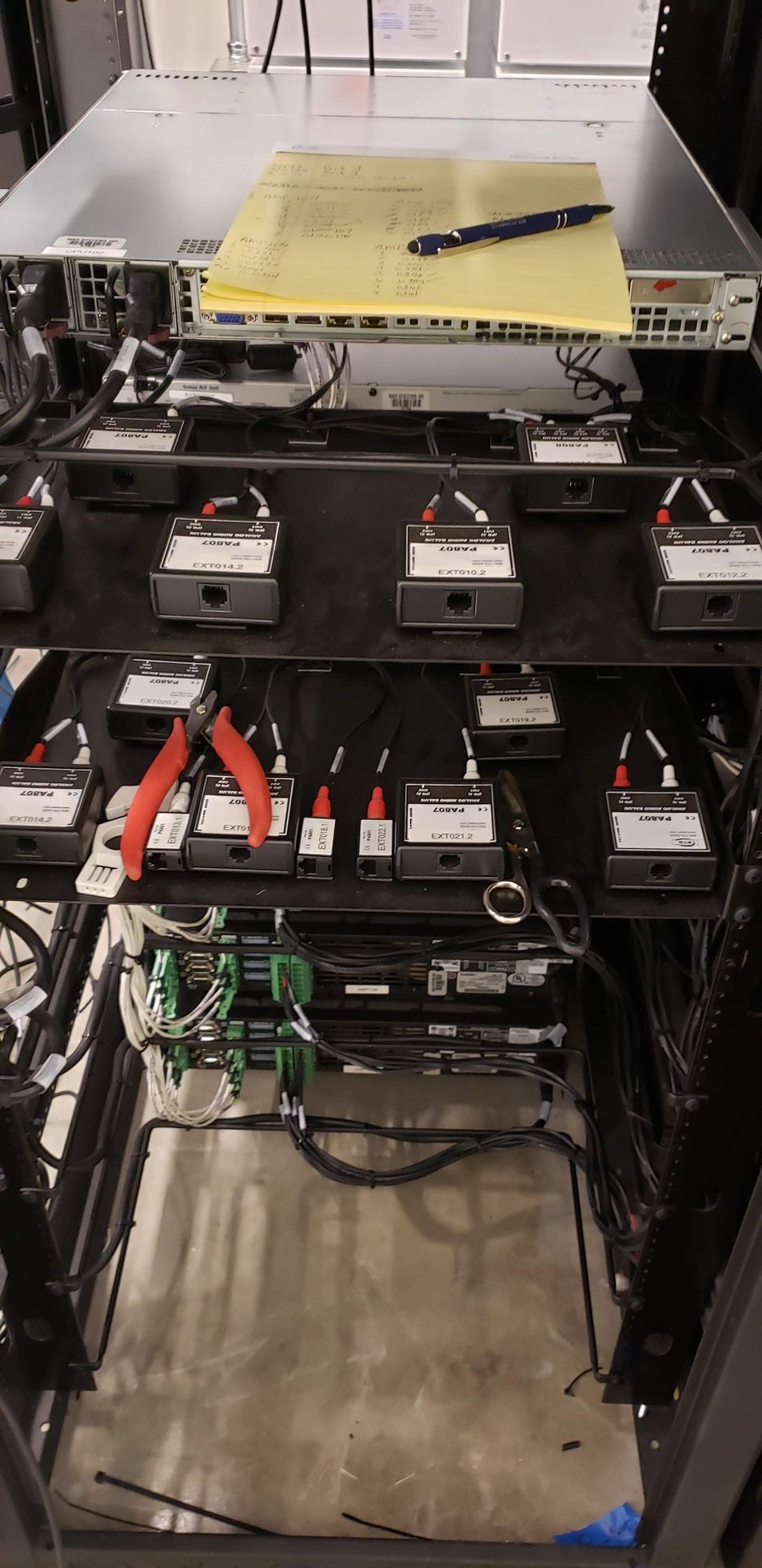 A server rack with a lot of wires and a pen on top of it.