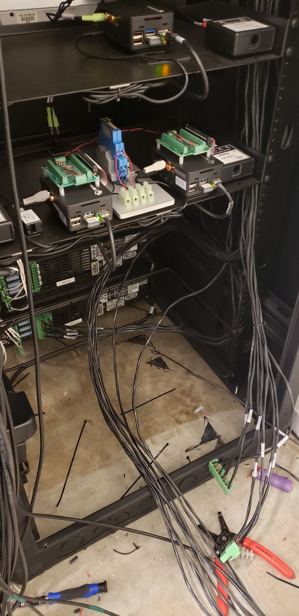 A bunch of wires are hanging from a rack on the floor.