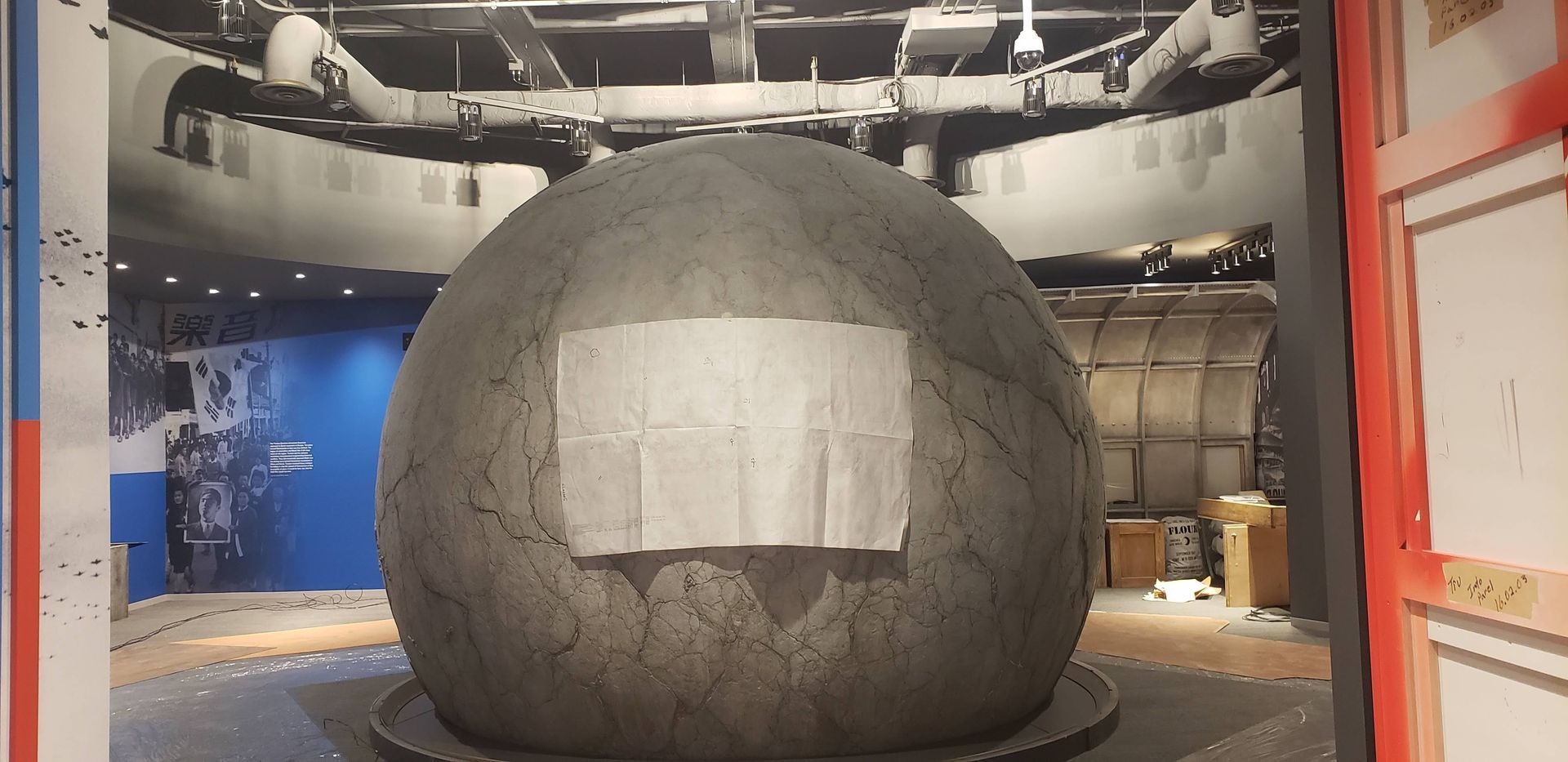 A large stone ball with a sign on it in a room.