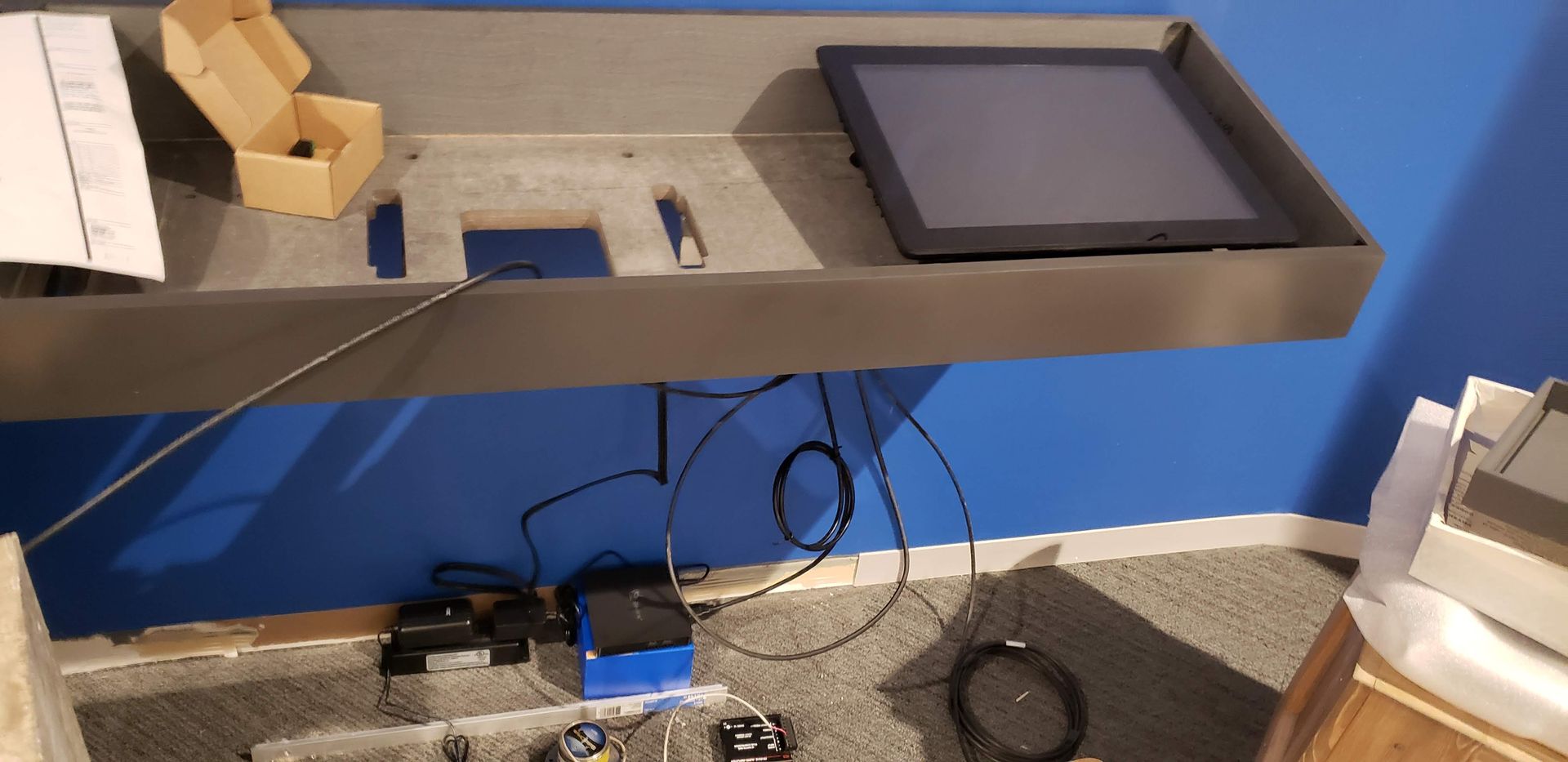 A tablet is sitting on top of a shelf in a room.