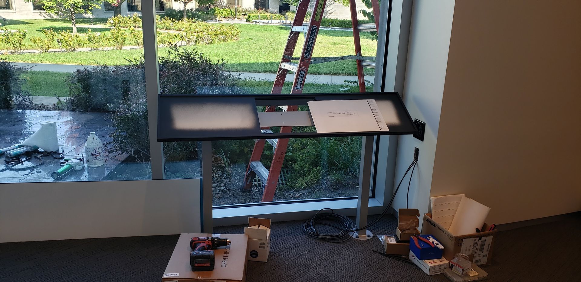 A room with a table and a ladder in front of a window.