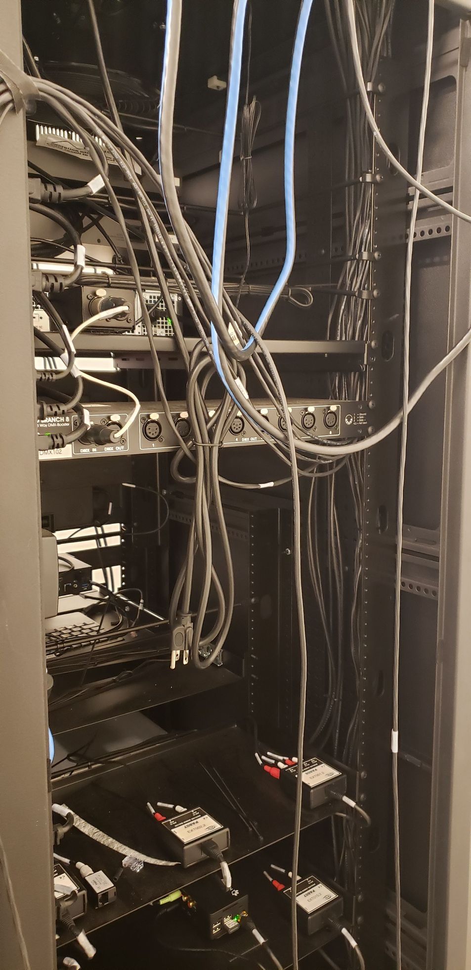 A server rack with a lot of wires hanging from it.