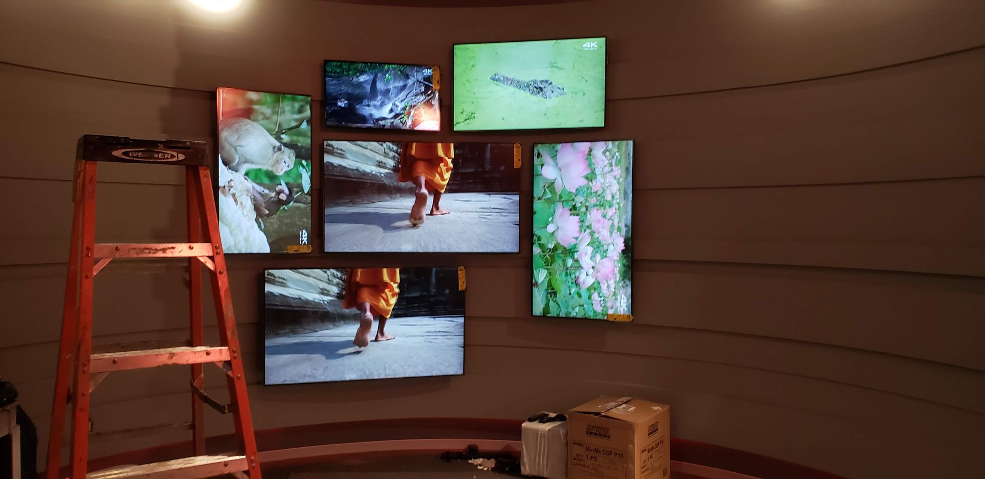 A room with a ladder and a bunch of televisions on the wall