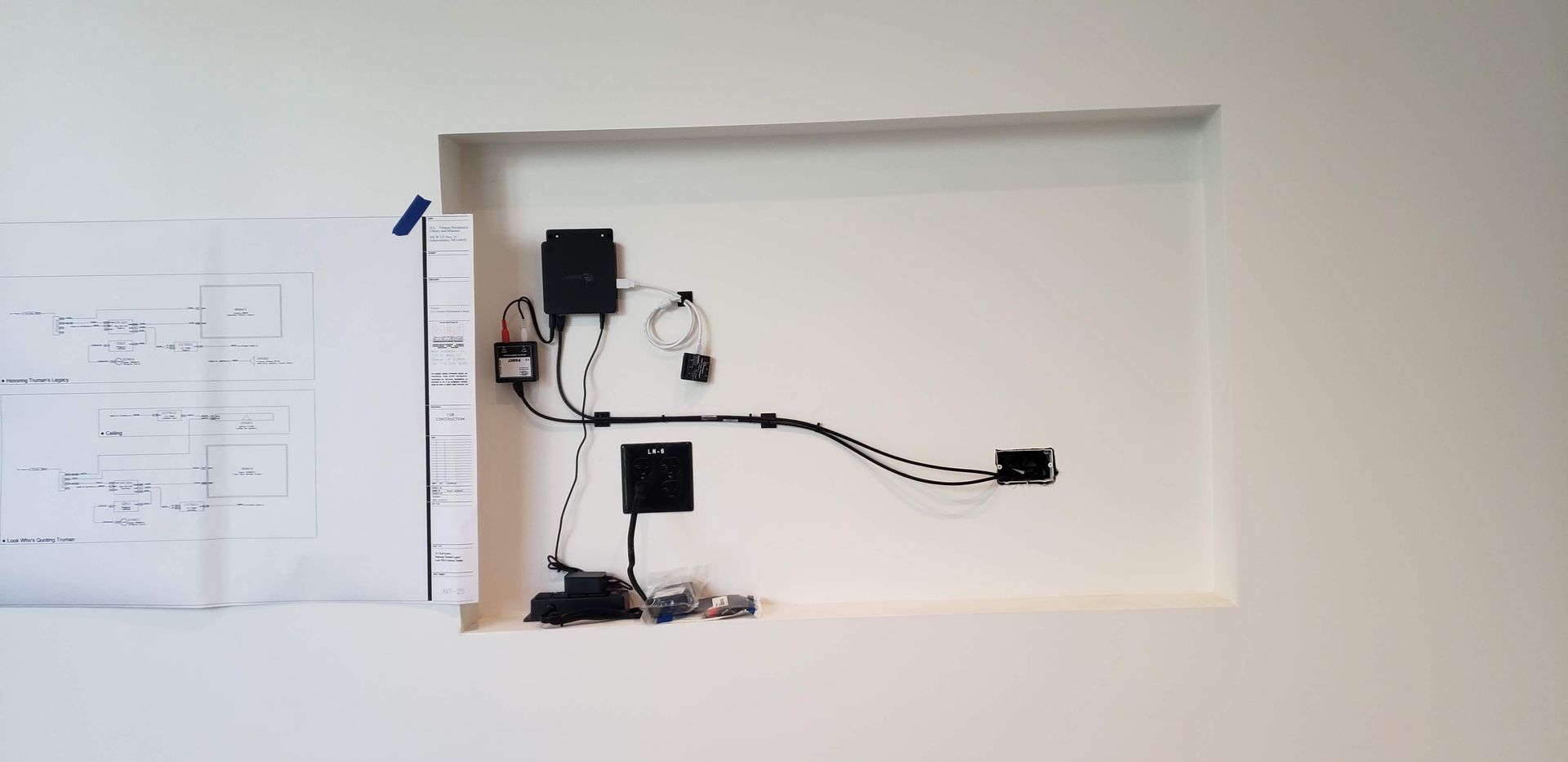 A white wall with a hole in it and a bunch of wires coming out of it.