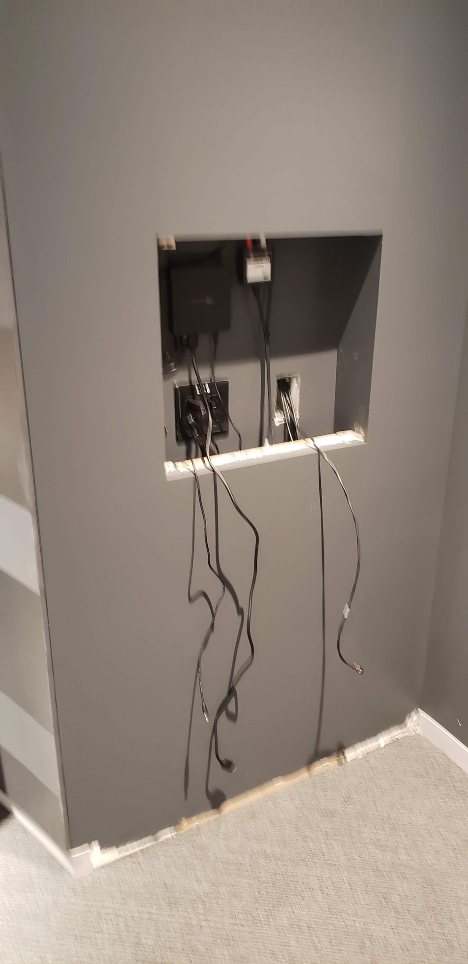 There is a hole in the wall with wires coming out of it.