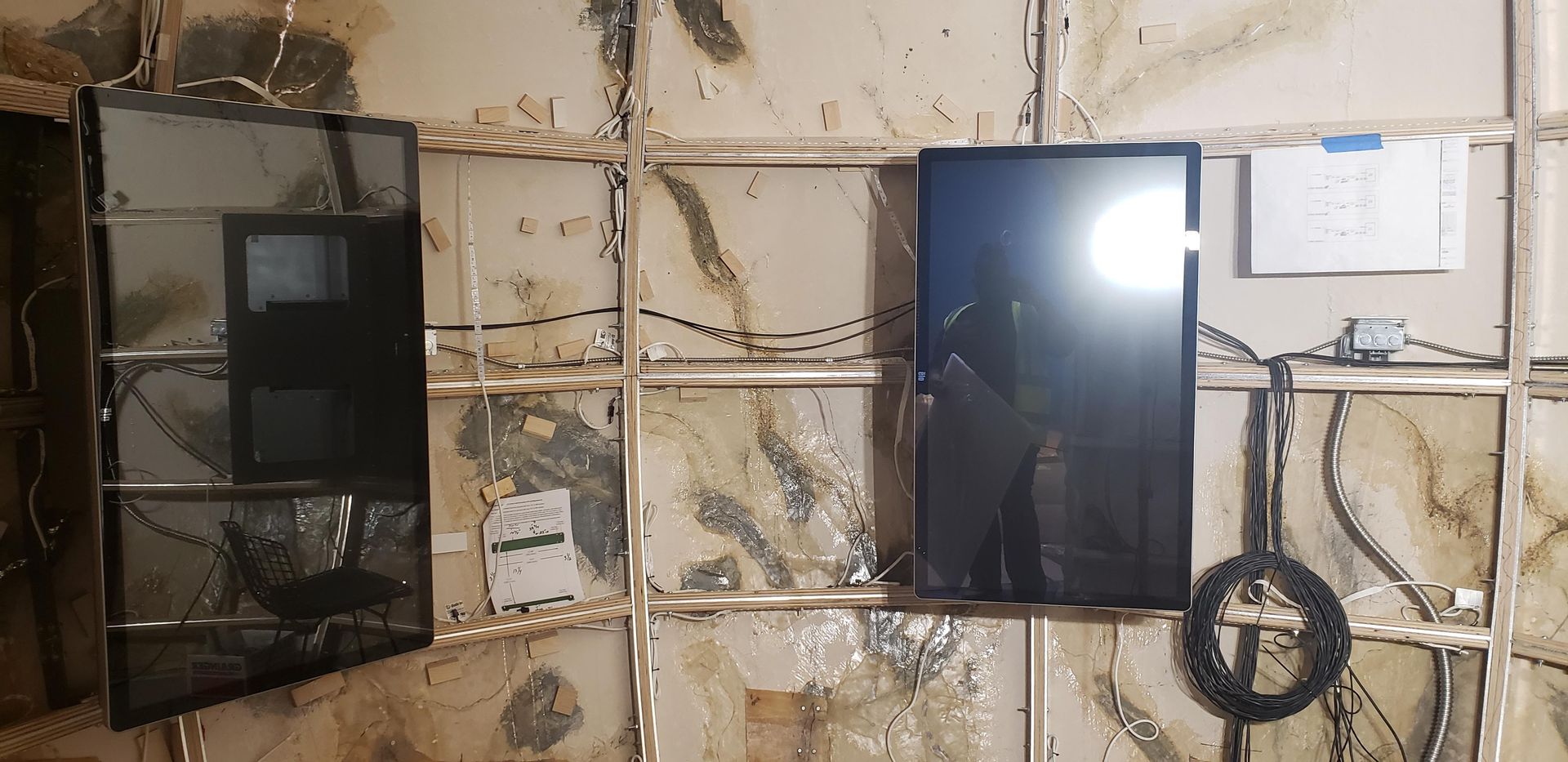 Two televisions are hanging on a wall in a room.