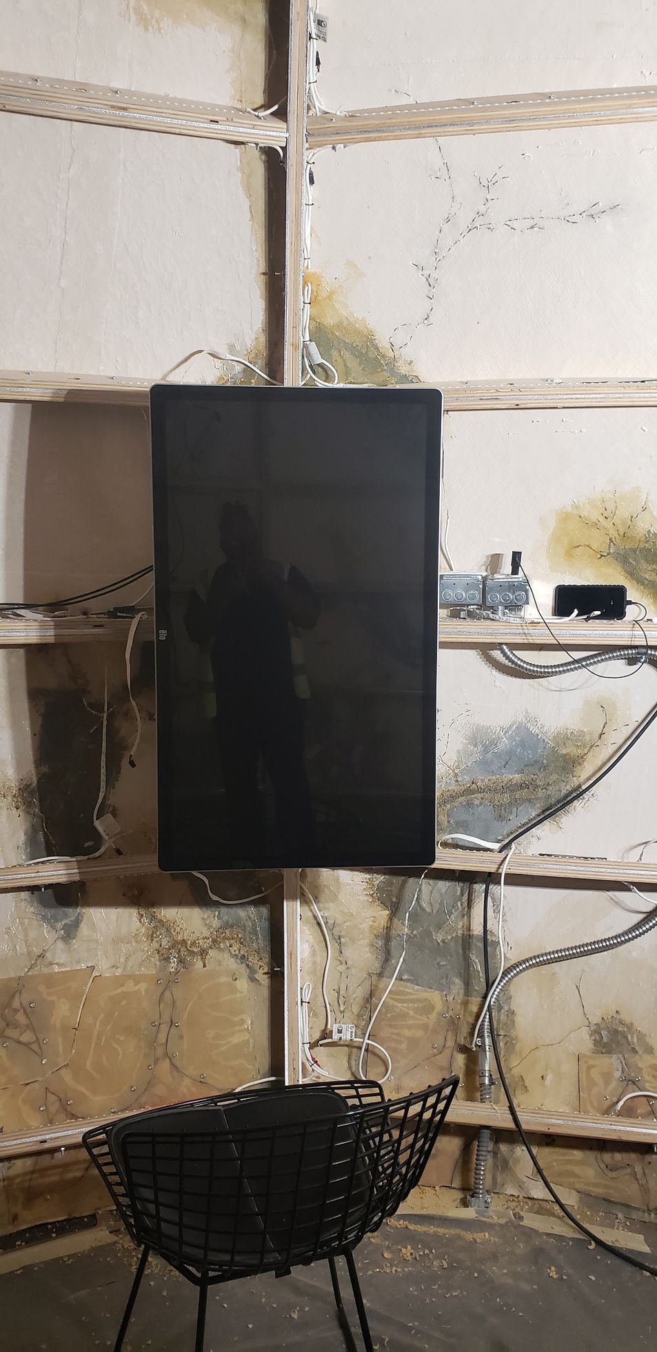 A tv is hanging on a wall next to a chair.