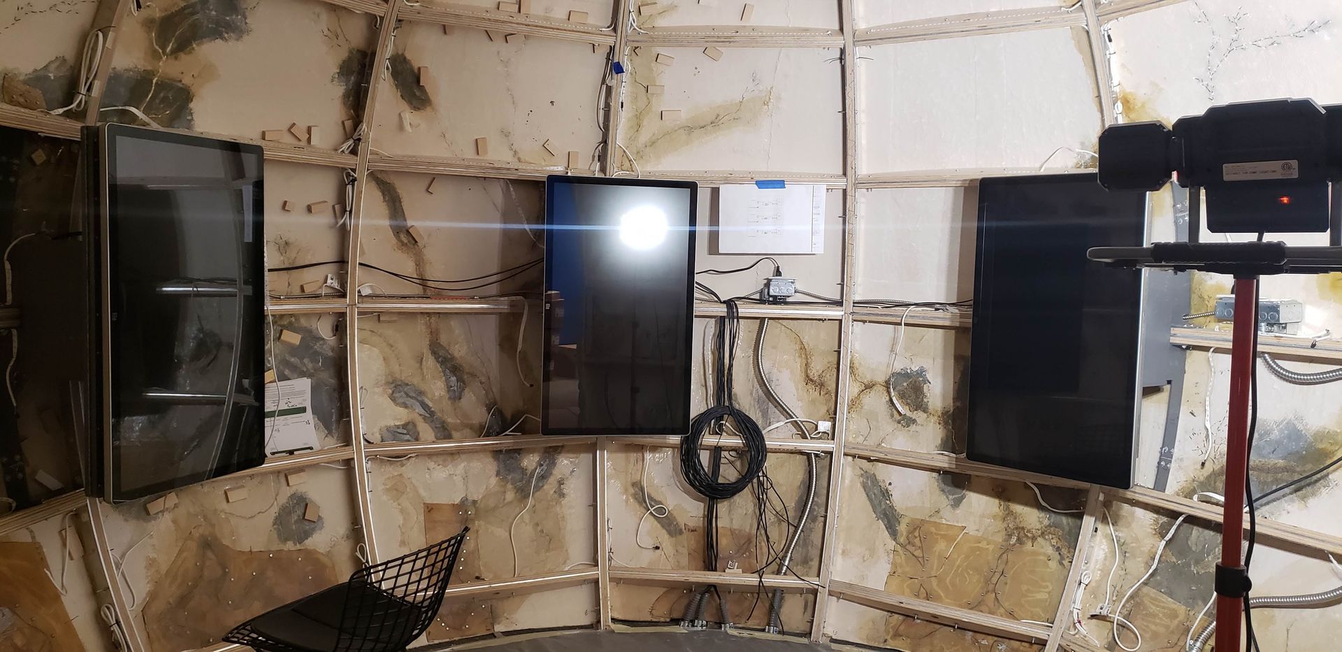 A room with a television and a camera on a tripod.