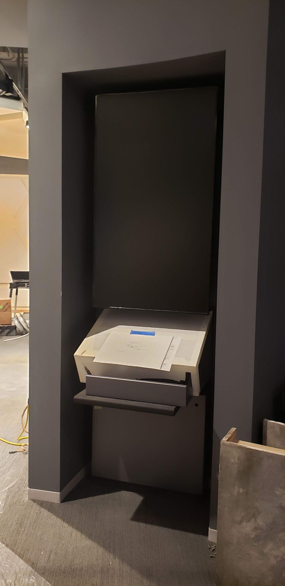 A printer is sitting in a corner of a room.