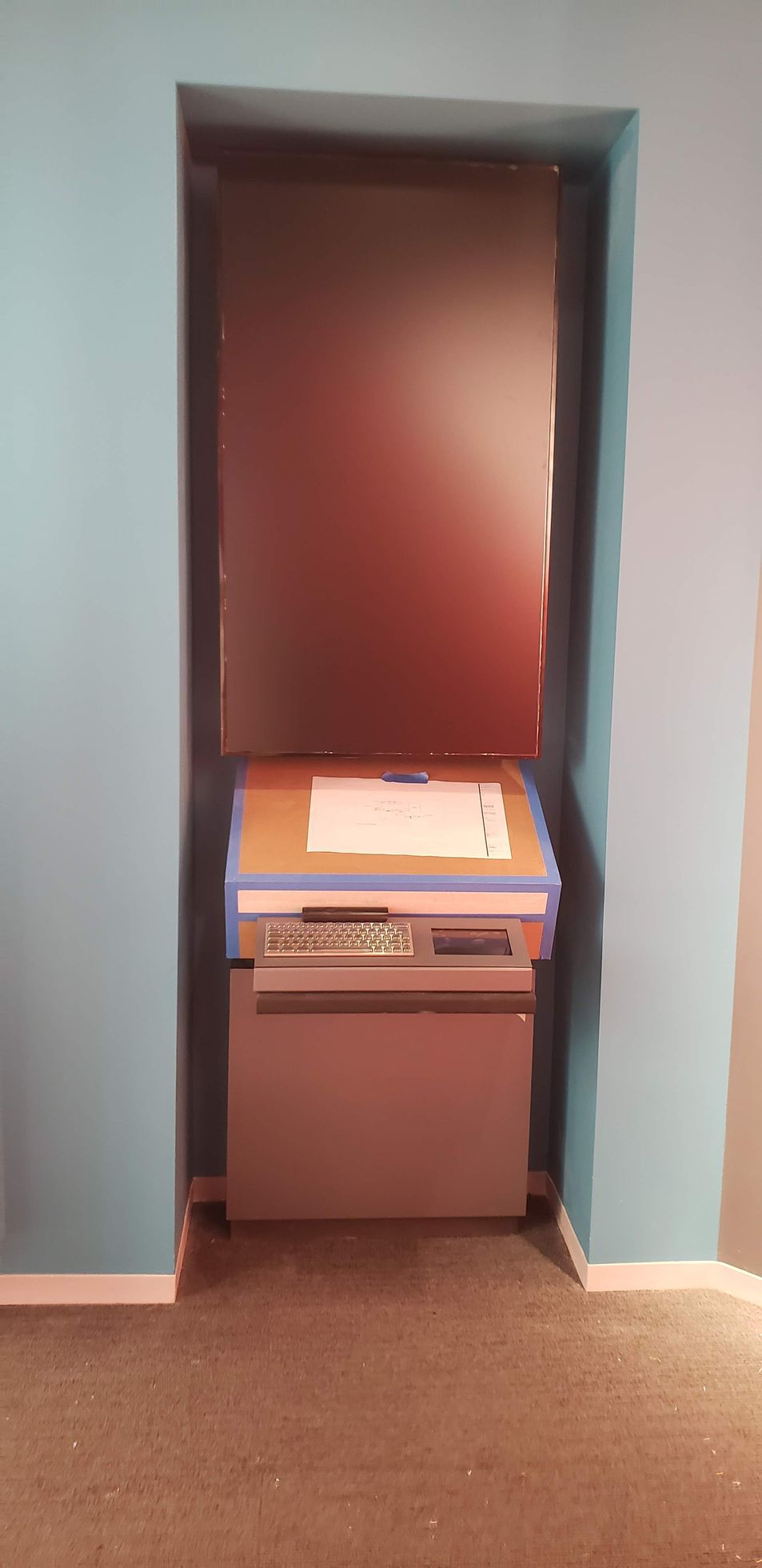 A small cabinet is sitting in a corner of a room next to a wall.