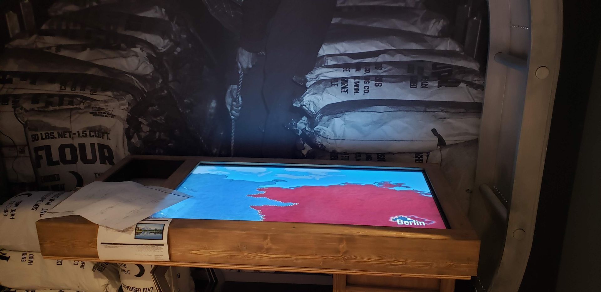 A table with a screen on it and a bag of flour on the wall behind it.