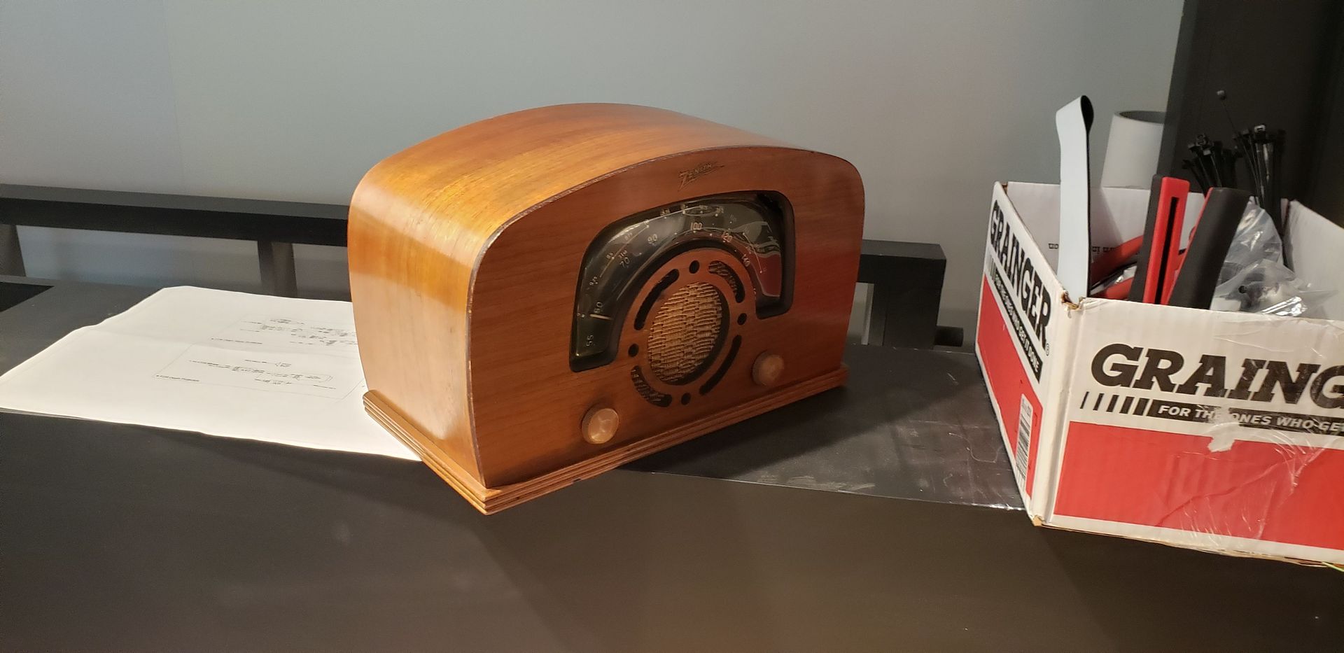 A small wooden radio is sitting on a table next to a box that says graing.